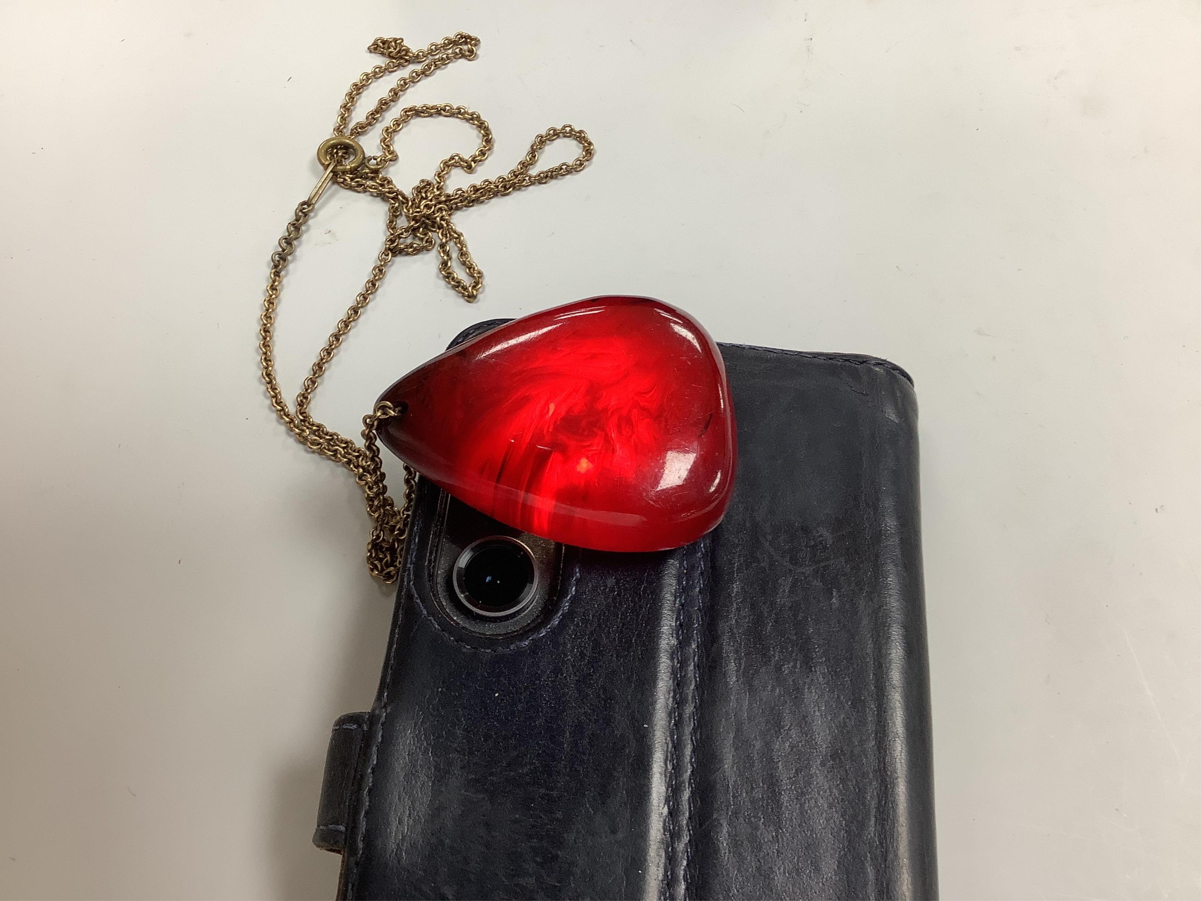 A cherry bakelite 'amber' necklace and pendant, comprising: a necklace composed of cherry-coloured bakelite beads measuring approximately 10 - 26mm, length 90cm, gross weight 72 grams; and a drop-shaped pendant, length 5